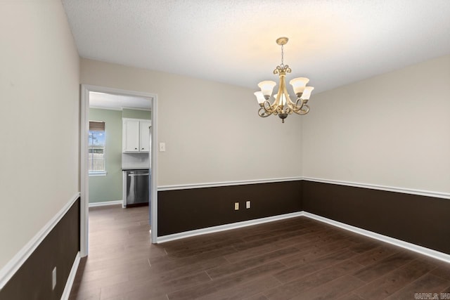 unfurnished room featuring baseboards, a textured ceiling, wood finished floors, and a notable chandelier