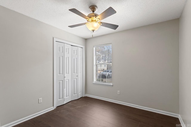 unfurnished bedroom with baseboards, dark wood-style floors, ceiling fan, a textured ceiling, and a closet