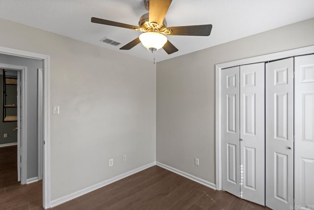 unfurnished bedroom featuring a ceiling fan, visible vents, baseboards, a closet, and dark wood finished floors