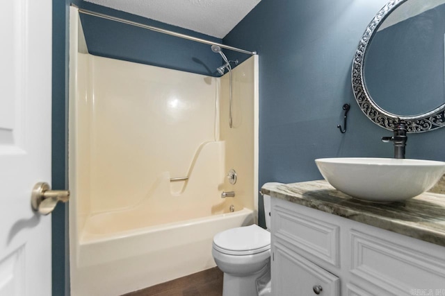 bathroom featuring a textured ceiling, bathtub / shower combination, toilet, wood finished floors, and vanity