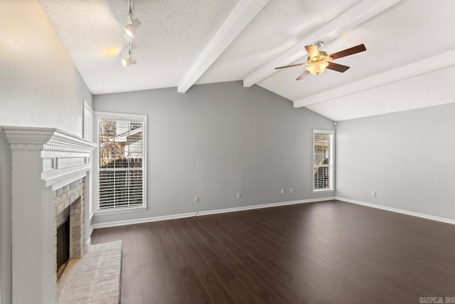 unfurnished living room with a textured ceiling, lofted ceiling with beams, a brick fireplace, and a wealth of natural light