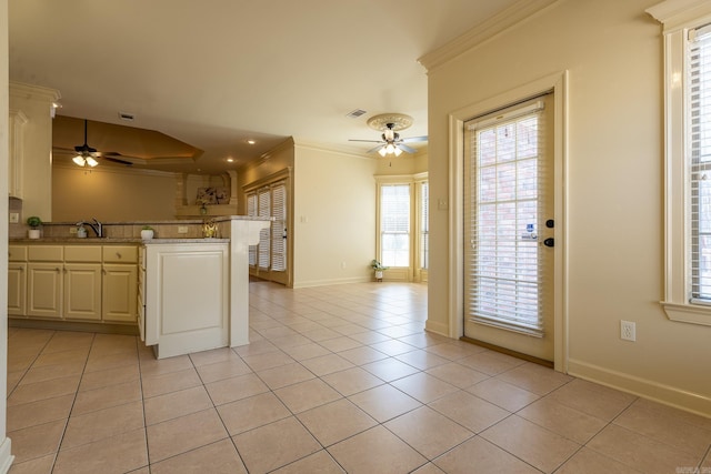 kitchen with ornamental molding, ceiling fan, a peninsula, and light tile patterned floors