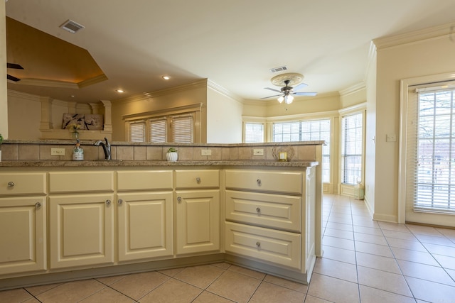 kitchen with ornamental molding, a wealth of natural light, visible vents, and ceiling fan