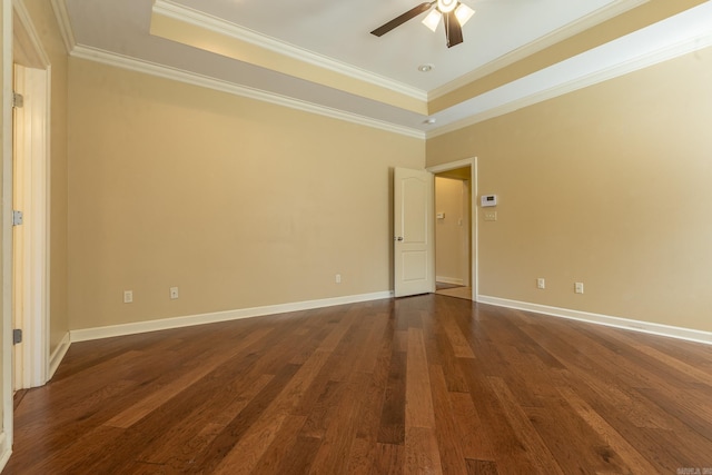 spare room featuring ceiling fan, dark wood-type flooring, baseboards, a tray ceiling, and crown molding