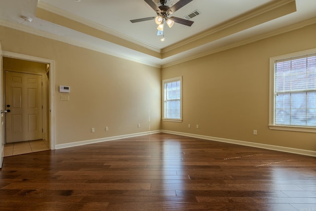 spare room with ornamental molding, a tray ceiling, visible vents, and hardwood / wood-style flooring