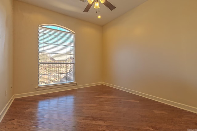 empty room with ceiling fan, baseboards, vaulted ceiling, and dark wood-type flooring