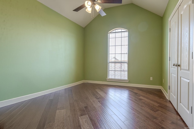 unfurnished room featuring a wealth of natural light, vaulted ceiling, dark wood finished floors, and baseboards