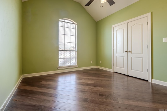 unfurnished bedroom with baseboards, a ceiling fan, dark wood-style flooring, vaulted ceiling, and a closet