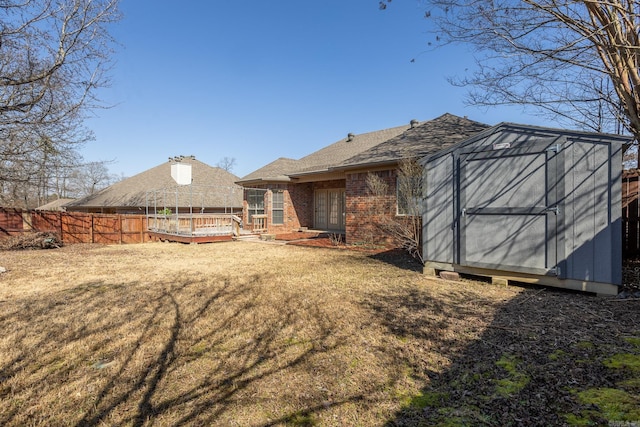 rear view of house with an outbuilding, a storage unit, fence, a wooden deck, and brick siding