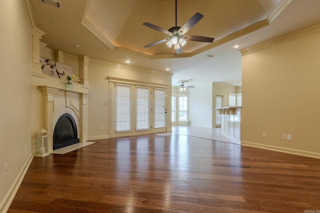 unfurnished living room featuring a tray ceiling, wood finished floors, and a tile fireplace