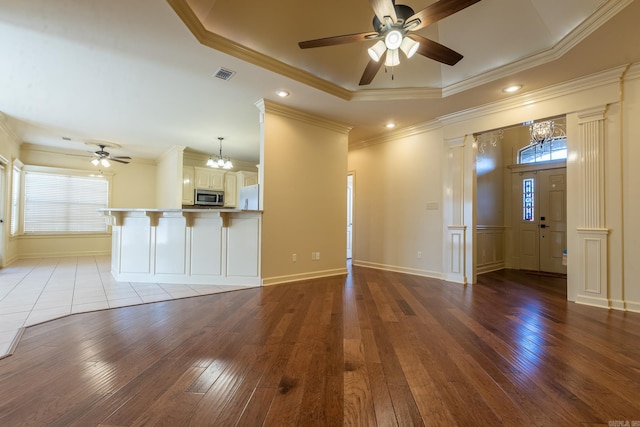 unfurnished living room with visible vents, a raised ceiling, baseboards, wood-type flooring, and ceiling fan with notable chandelier