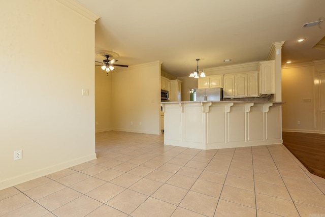 kitchen featuring stainless steel appliances, a peninsula, light tile patterned flooring, and crown molding