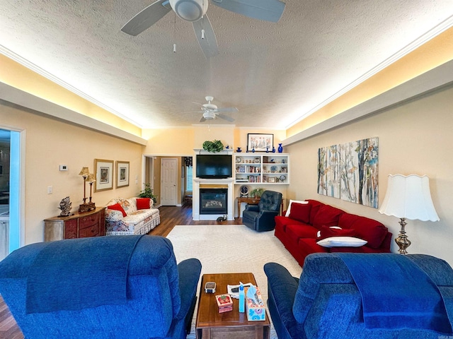 2407 Brittany, Searcy, AR 72143 - living area featuring a ceiling fan, a glass covered fireplace, ornamental molding, wood finished floors, and a textured ceiling