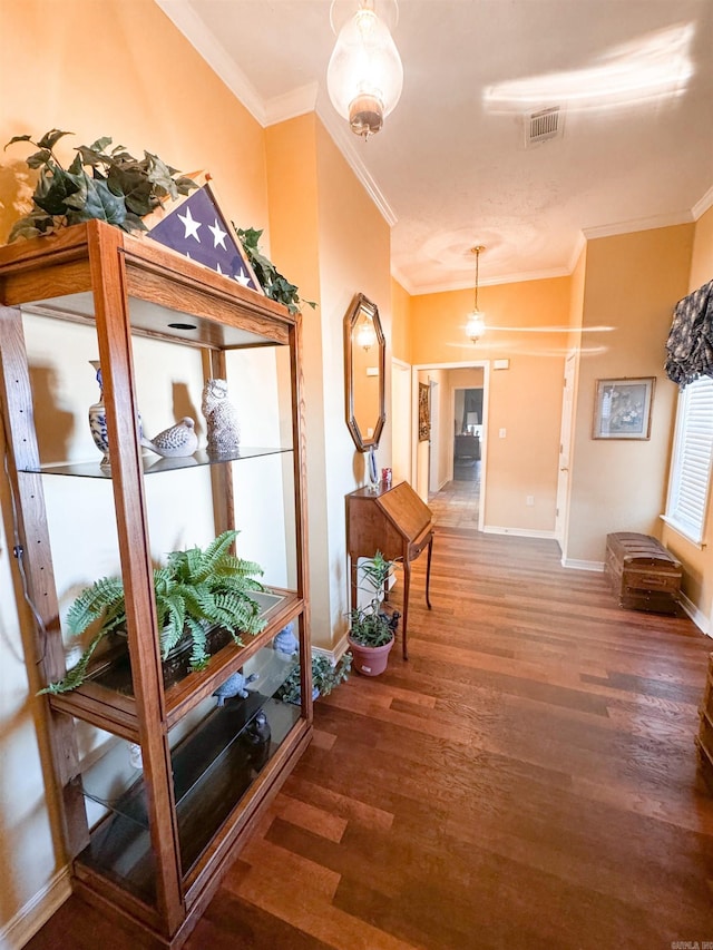 hall featuring crown molding, baseboards, and wood finished floors