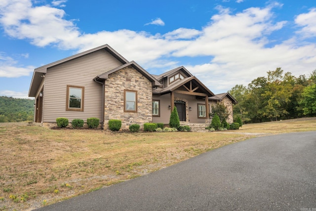 craftsman house with stone siding and a front yard