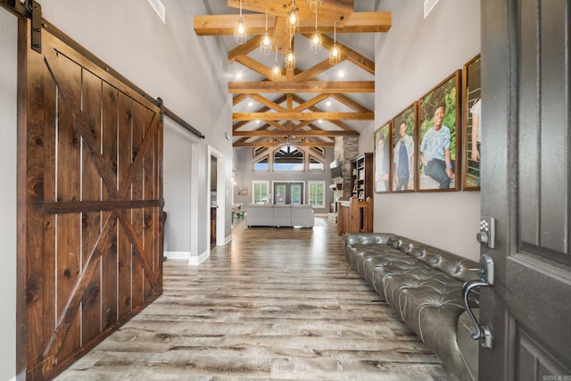 foyer featuring a chandelier, high vaulted ceiling, a barn door, wood finished floors, and beam ceiling