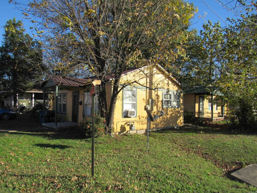 view of front of home featuring metal roof, a front lawn, cooling unit, and stucco siding