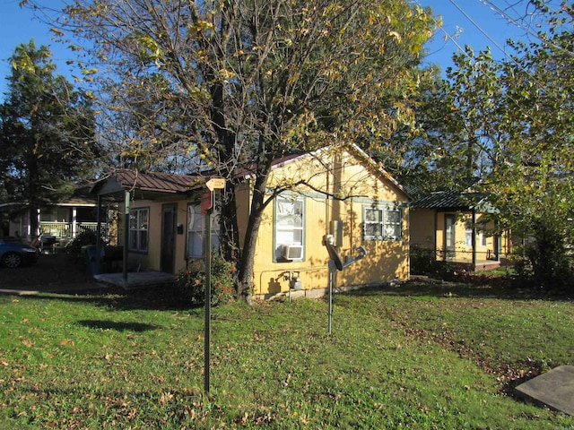 view of front of home featuring metal roof, a front lawn, cooling unit, and stucco siding