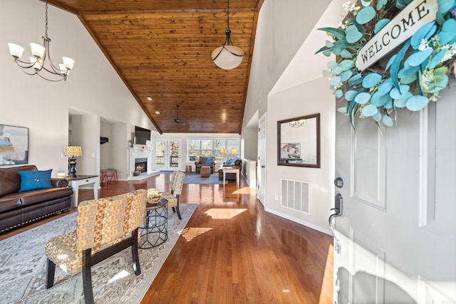 foyer featuring wood ceiling, visible vents, a lit fireplace, and wood finished floors