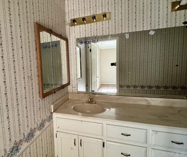 bathroom with a wainscoted wall, vanity, and wallpapered walls