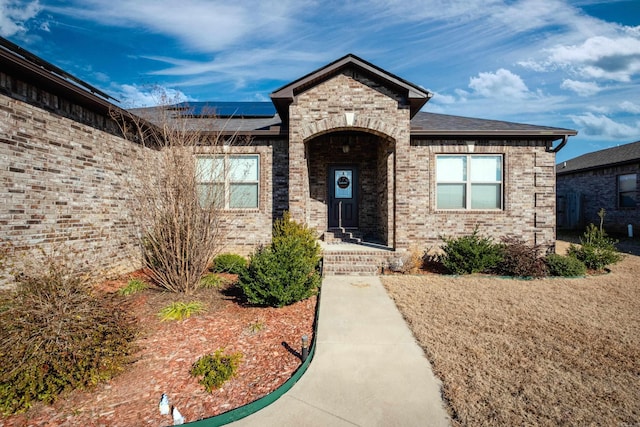 property entrance featuring brick siding and roof mounted solar panels