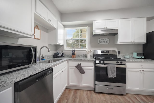 kitchen with stainless steel appliances, white cabinetry, a sink, light wood-type flooring, and under cabinet range hood