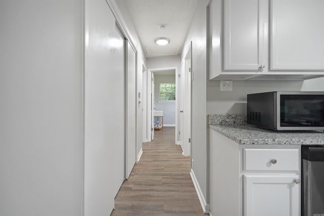 hall with light wood-type flooring and baseboards