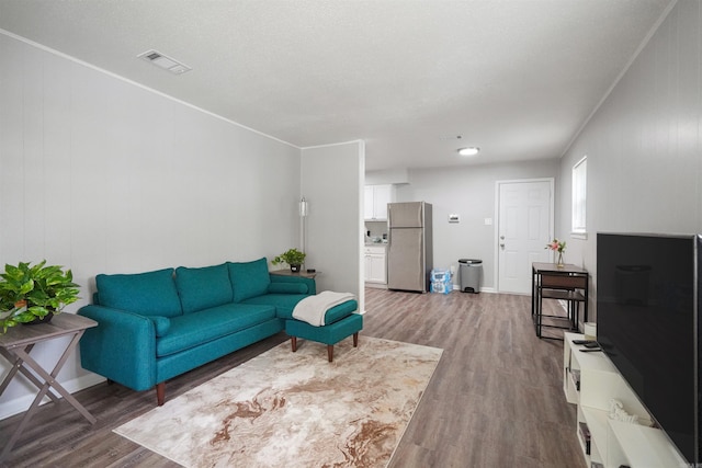 living room with ornamental molding, wood finished floors, and visible vents