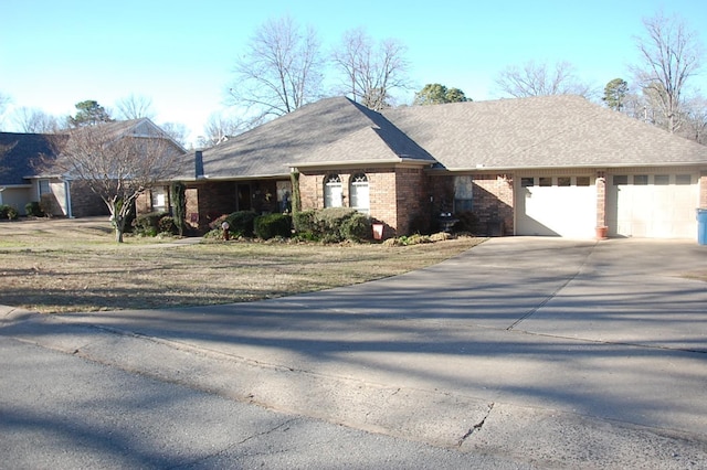 ranch-style home featuring a garage, a shingled roof, concrete driveway, and brick siding