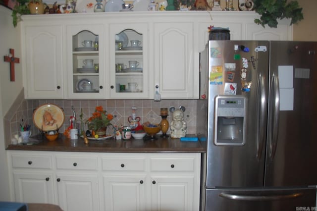 kitchen with glass insert cabinets, stainless steel fridge, white cabinetry, and tasteful backsplash