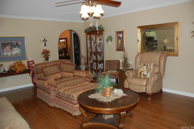 living area featuring ornamental molding, arched walkways, baseboards, and wood finished floors