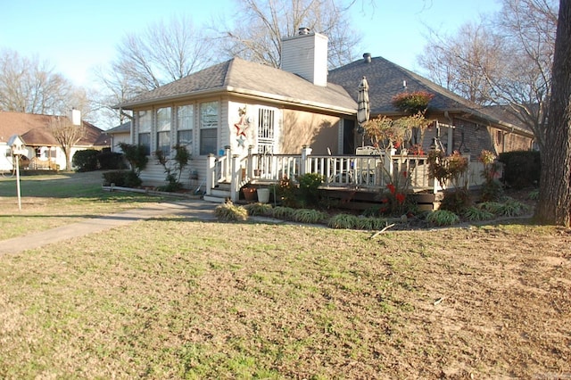 back of property with a lawn, a chimney, and a wooden deck