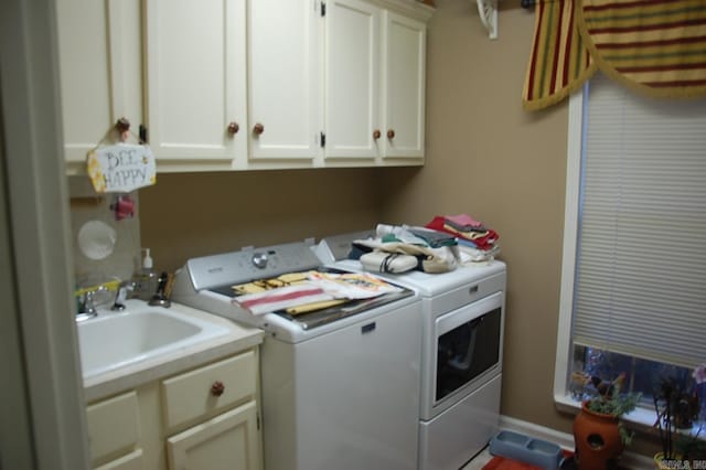 clothes washing area featuring washing machine and dryer, cabinet space, and a sink