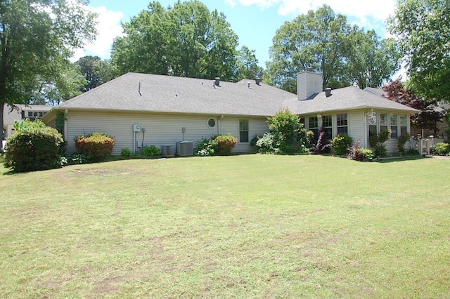 back of property featuring a lawn, cooling unit, and a chimney