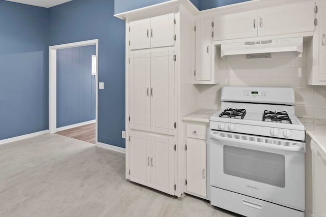 kitchen featuring white gas range oven, baseboards, white cabinets, light countertops, and under cabinet range hood