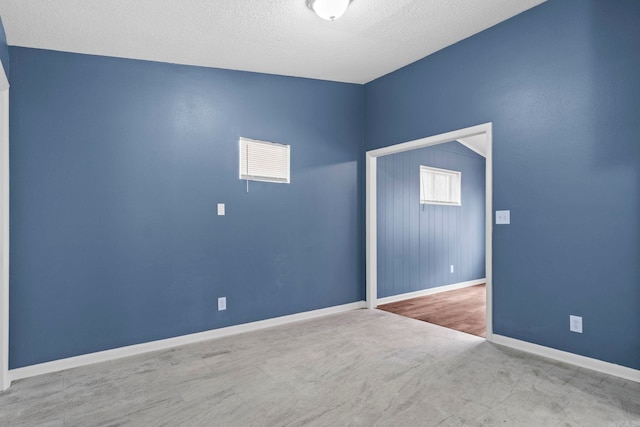 empty room featuring a textured ceiling and baseboards