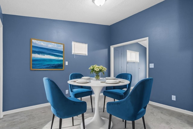 dining space with a textured ceiling and baseboards