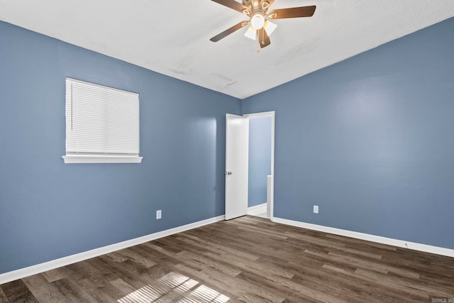 spare room with a ceiling fan, lofted ceiling, baseboards, and wood finished floors