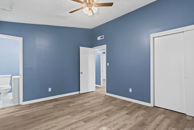 unfurnished bedroom featuring baseboards, a closet, visible vents, and wood finished floors