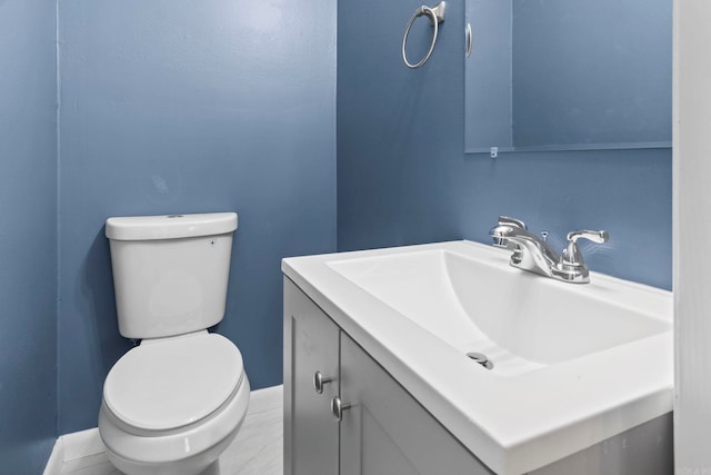 half bathroom featuring toilet, vanity, and baseboards