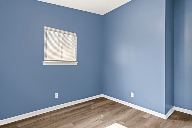 unfurnished room with baseboards and wood finished floors