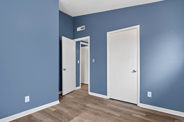 unfurnished bedroom with visible vents, baseboards, and wood finished floors