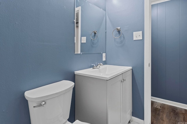 bathroom with baseboards, vanity, toilet, and wood finished floors