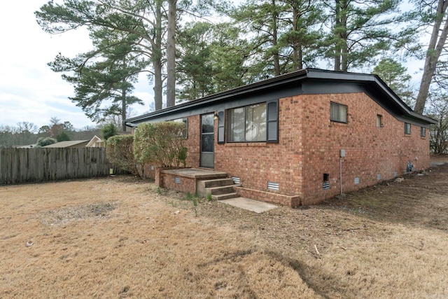 view of front of house with crawl space, brick siding, and fence