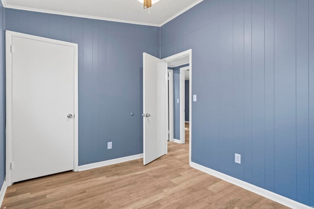 interior space with ornamental molding, wood finished floors, a ceiling fan, and baseboards