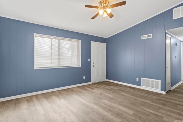 empty room with vaulted ceiling, wood finished floors, and visible vents