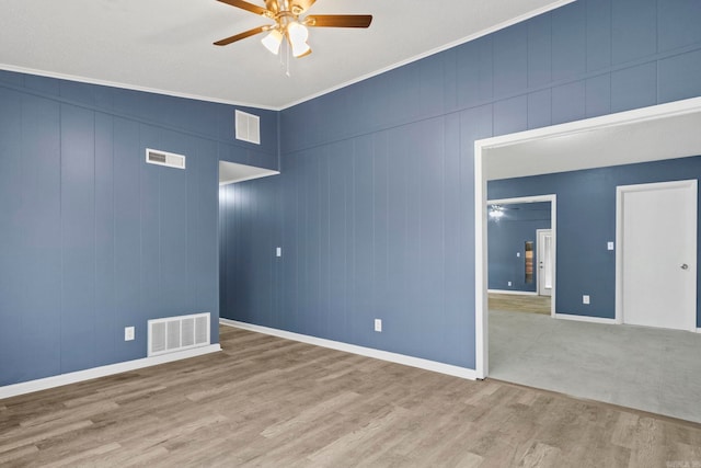 empty room featuring ceiling fan, visible vents, and wood finished floors