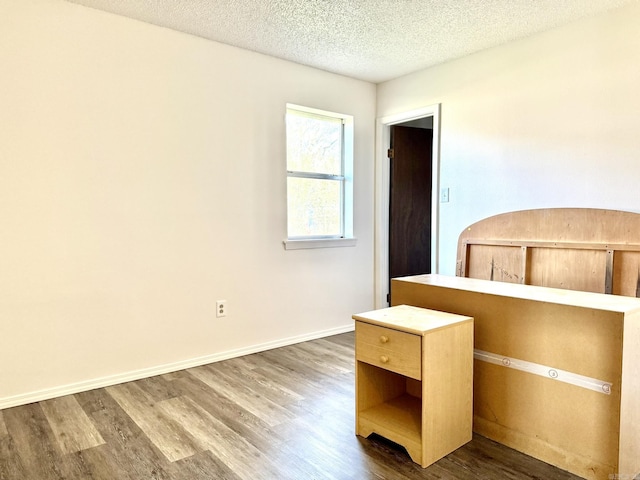 unfurnished bedroom with baseboards, dark wood finished floors, and a textured ceiling