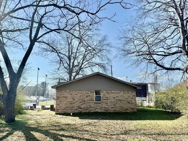 view of property exterior featuring brick siding, a lawn, and central AC