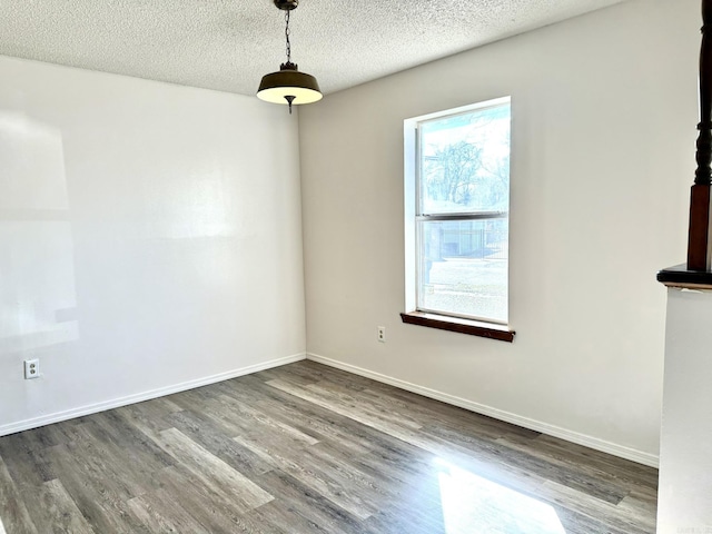 spare room with a textured ceiling, dark wood-style flooring, and baseboards